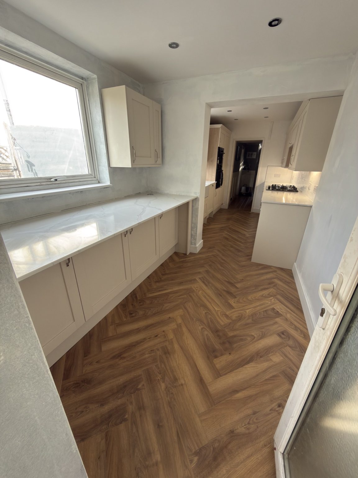 Renovated kitchen and adjoining room with herringbone flooring